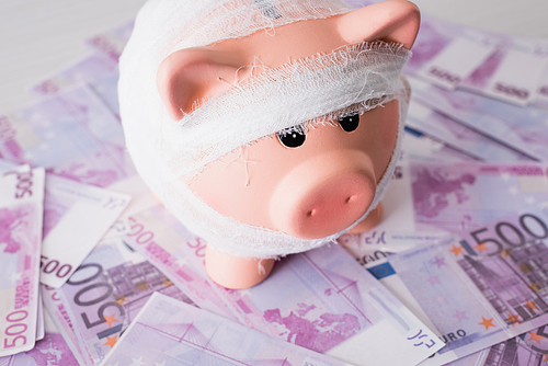 Selective focus of piggy bank with bandage on money