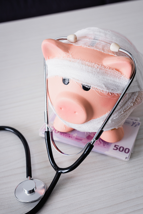 High angle view of piggy bank on table with stethoscope