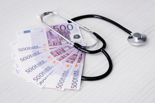 Selective focus of stethoscope and euro banknotes on white table