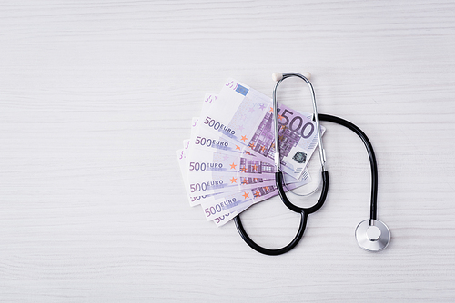 Top view of stethoscope and euro banknotes on white table