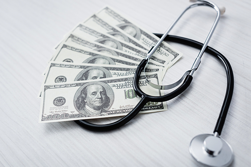 Selective focus of stethoscope and dollar banknotes on white table