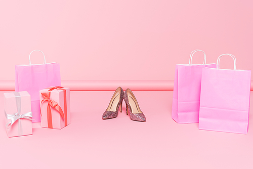 heels near shopping bags and gift boxes on pink