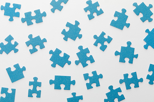 top view of scattered blue jigsaw puzzle on white background