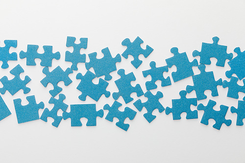 top view of scattered pieces of blue jigsaw puzzle on white background