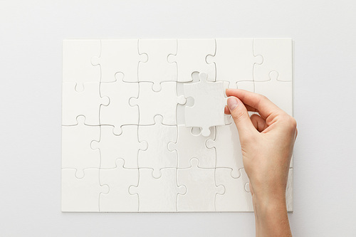 cropped view of woman completing jigsaw puzzle on white background
