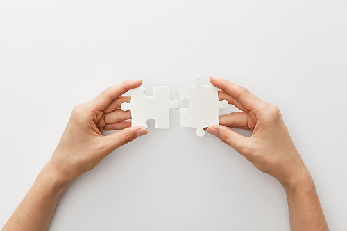 cropped view of woman holding piece of jigsaw puzzle on white background