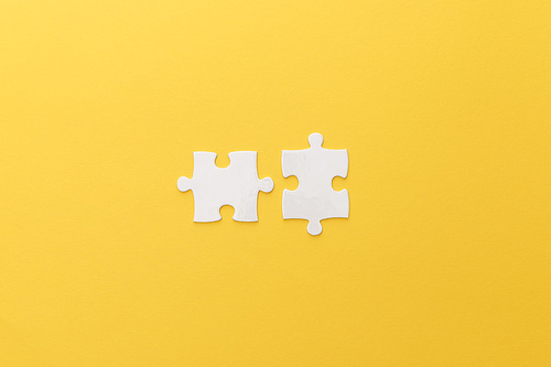 top view of white puzzle pieces on yellow background