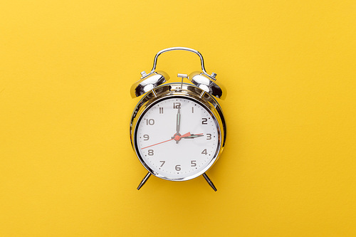 top view metal clock on yellow background
