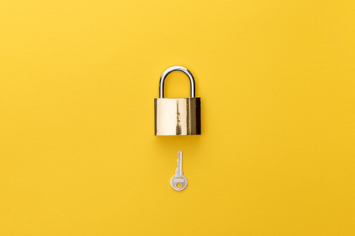 top view of padlock and key on yellow background