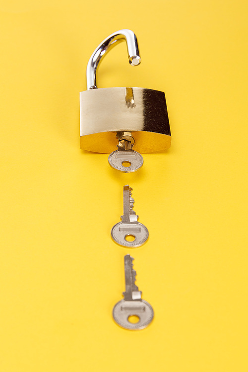 metal padlock with keys on yellow background