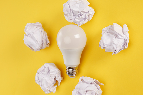 top view of crumpled paper and lamp on yellow background