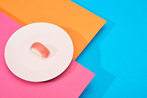 fresh nigiri with tuna on pink, blue, orange surface