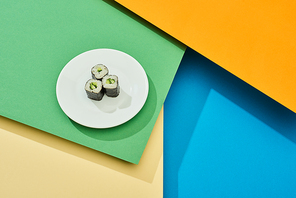 fresh maki with cucumber on plate on multicolored surface