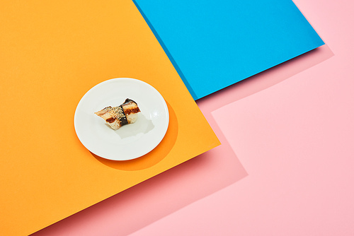 fresh nigiri with eel on plate on blue, pink, orange surface