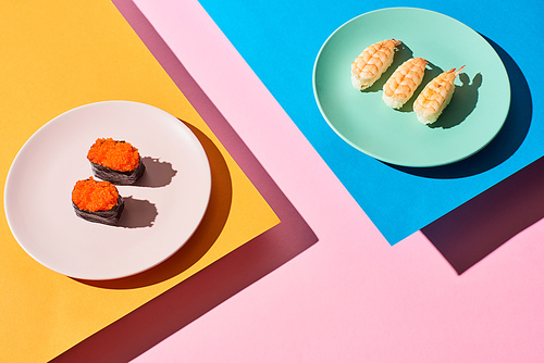 fresh nigiri with shrimps and red caviar on blue, pink, orange background
