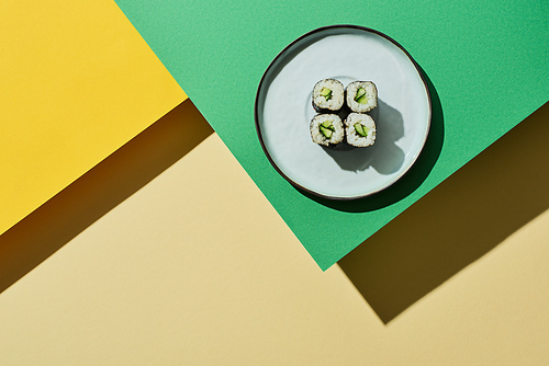 top view of fresh nigiri with cucumber on green and yellow surface