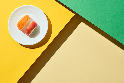 top view of fresh nigiri with salmon and tuna on green and yellow surface