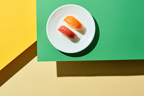 top view of fresh nigiri with salmon and tuna on green and yellow surface