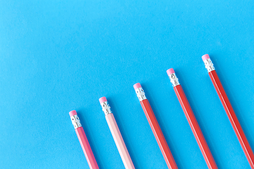 drawing, education and object concept - five lead pencils with eraser on tip on blue background