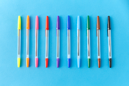 school, writing tools and object concept - row of many multicolored pens on blue background