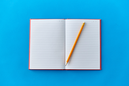 education and object concept - open notebook or diary with pencil on blue background