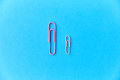 office supplies, stationery and object concept - pink clips on blue background