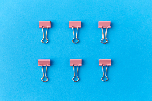 office supplies, stationery and object concept - binder clips on blue background