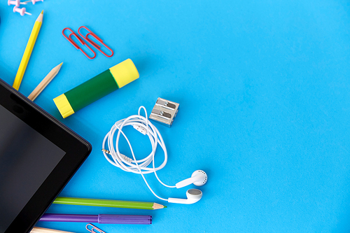 education, technology and object concept - tablet pc computer and stationery or school supplies on blue background