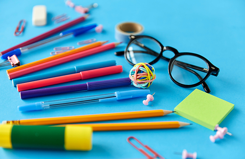 education, office and object concept - close up of stationery or school supplies on blue background