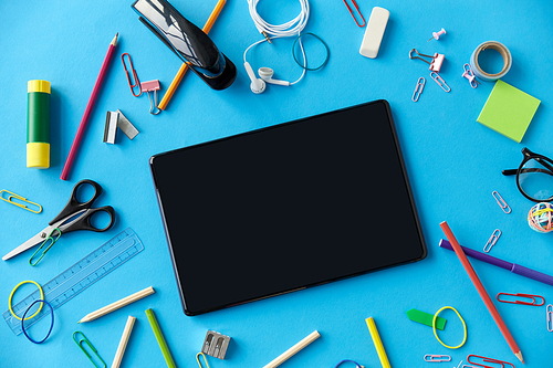 education, technology and object concept - tablet pc computer and stationery or school supplies on blue background