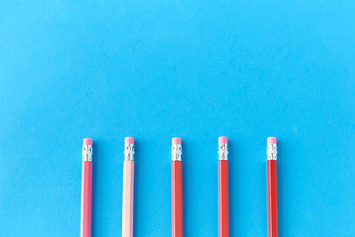 drawing, education and object concept - five lead pencils with eraser on tip on blue background