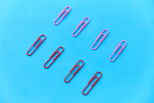 office supplies, stationery and object concept - clips on blue background