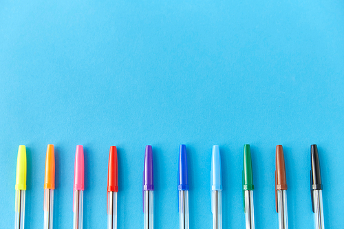 school, writing tools and object concept - row of many multicolored pens on blue background