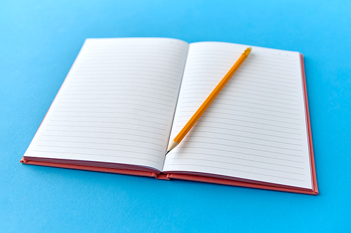 education and object concept - open notebook or diary with pencil on blue background