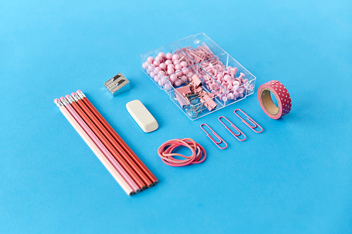 office supplies, stationery and object concept - pink pencil, pins and clips on blue background