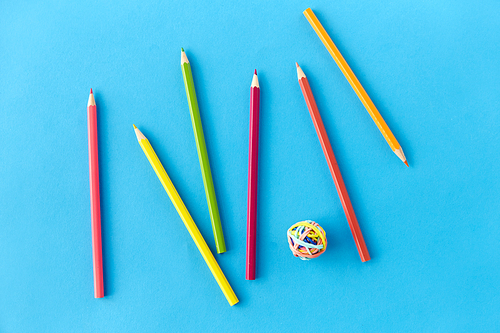 artistic tools, drawing, creativity and object concept - coloring pencils and rubber bands on blue background