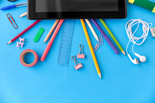 education, technology and object concept - tablet pc computer and stationery or school supplies on blue background