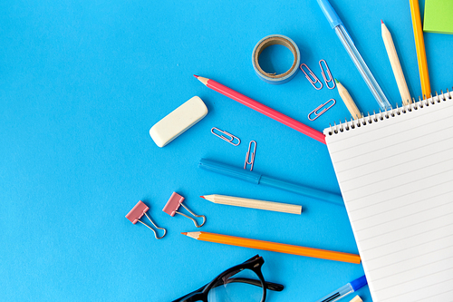 education, office and object concept - notebook and stationery or school supplies on blue background