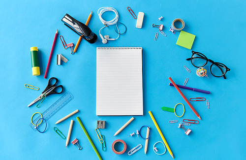 education, office and object concept - notebook and stationery or school supplies on blue background