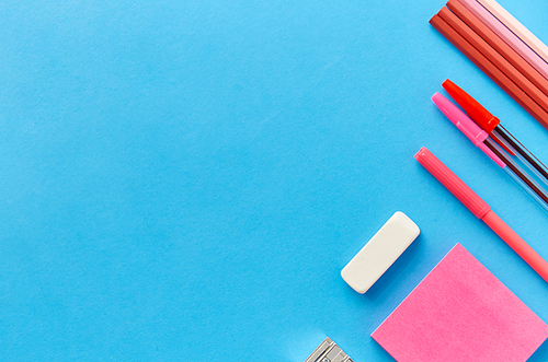 office supplies, stationery and object concept - pink sticky notes, clips, pens with pencils and eraser on blue background