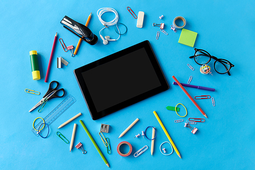 education, technology and object concept - tablet pc computer and stationery or school supplies on blue background