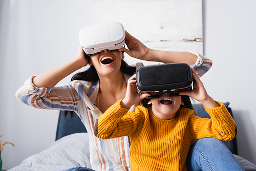 excited child with mother using vr headsets in bedroom