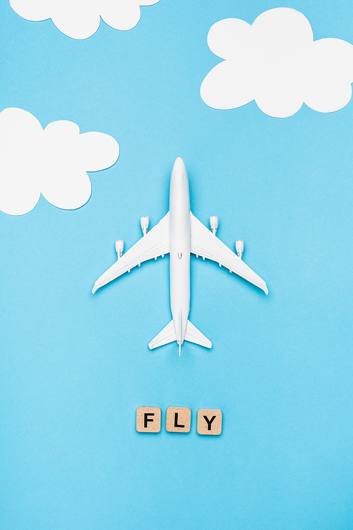 top view of plane model and cubes with word fly on blue sky background