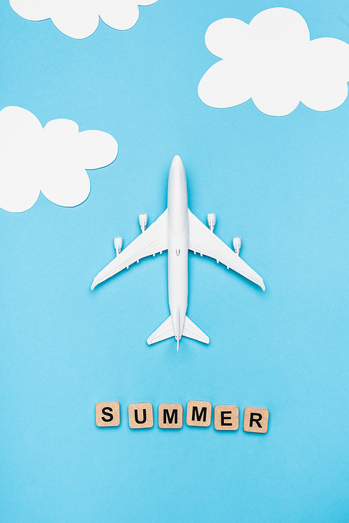 top view of plane model and cubes with word summer on blue sky background