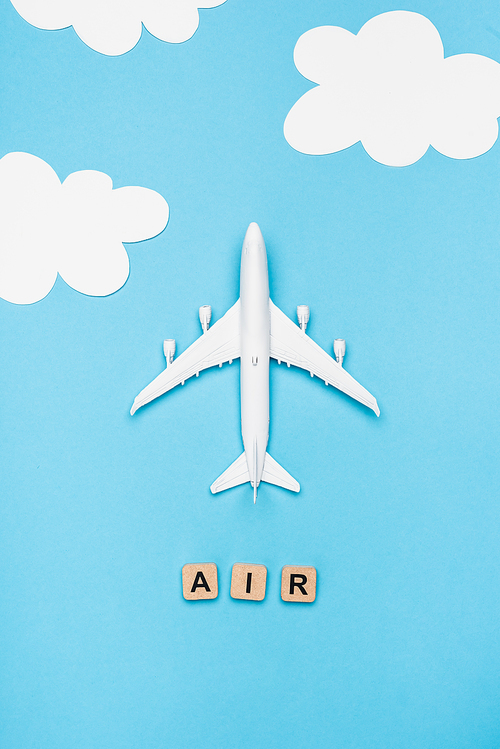 top view of plane model and cubes with word air on blue sky background