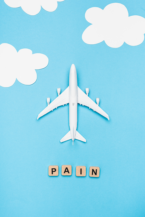 top view of plane model and cubes with word pain on blue sky background