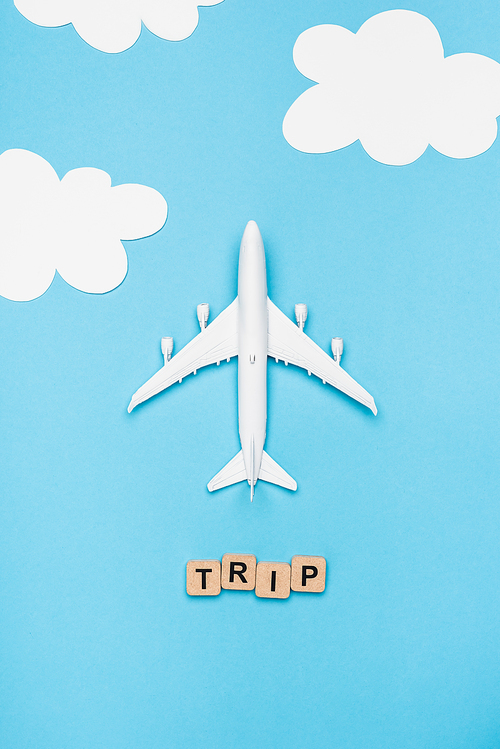 top view of plane model and cubes with word trip on blue sky background