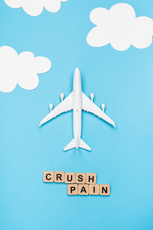 top view of plane model and cubes with word crush pain on blue sky background