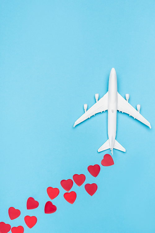 top view of plane model and red hearts on blue background