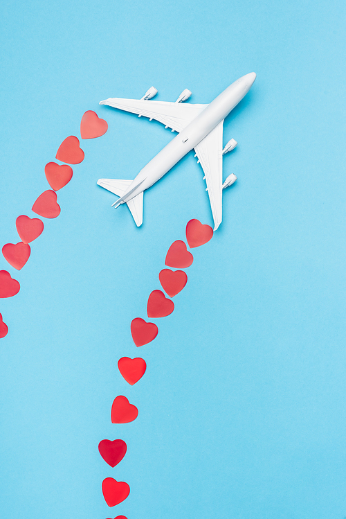 top view of plane model and red hearts on blue background